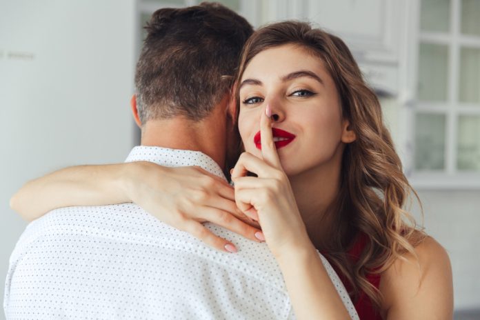 young-woman-making-silence-gesture-while-hug-her-husband