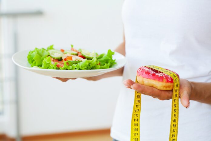 Woman holding a salad and a pink donut