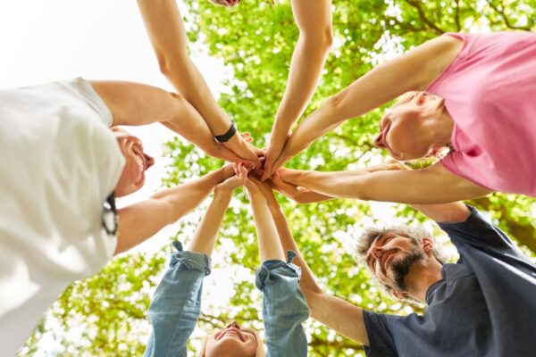 Grup de persoane unind mâinile în cerc afară