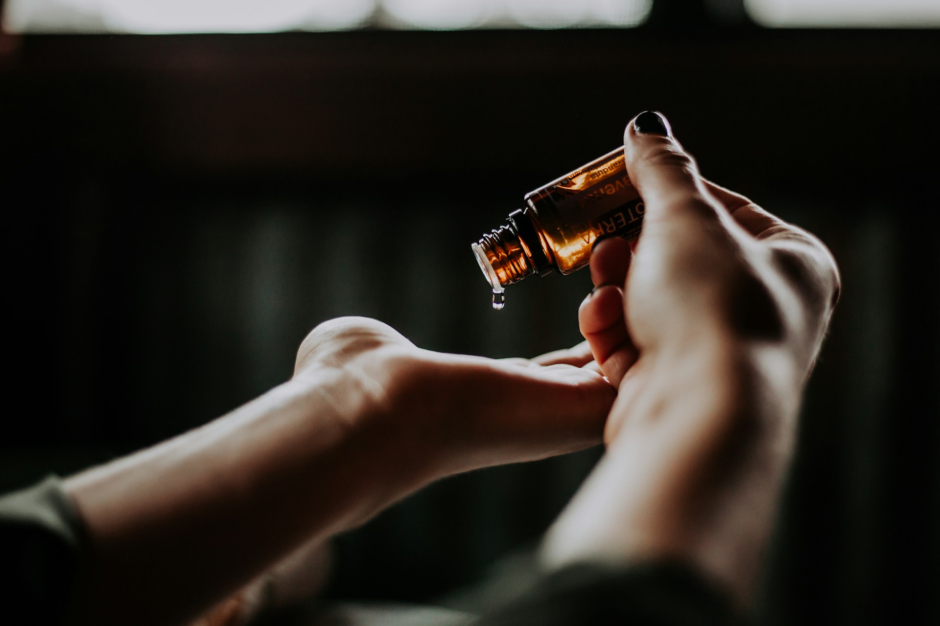 Mâini care aplică ulei esențial doTERRA din sticlă mică